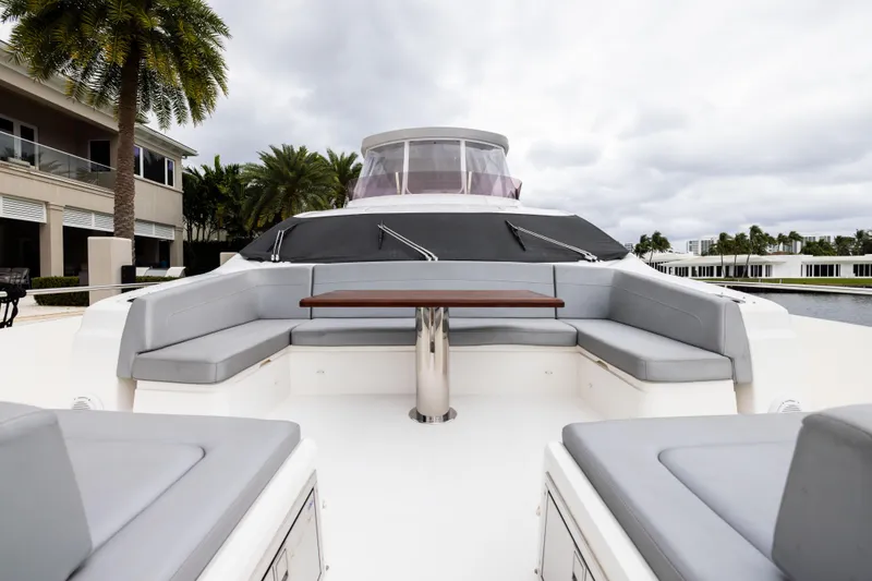 Journey Yacht Photos Pics Luxurious 2019 Sunseeker 76 yacht with spacious outdoor seating and table, docked near palm trees.