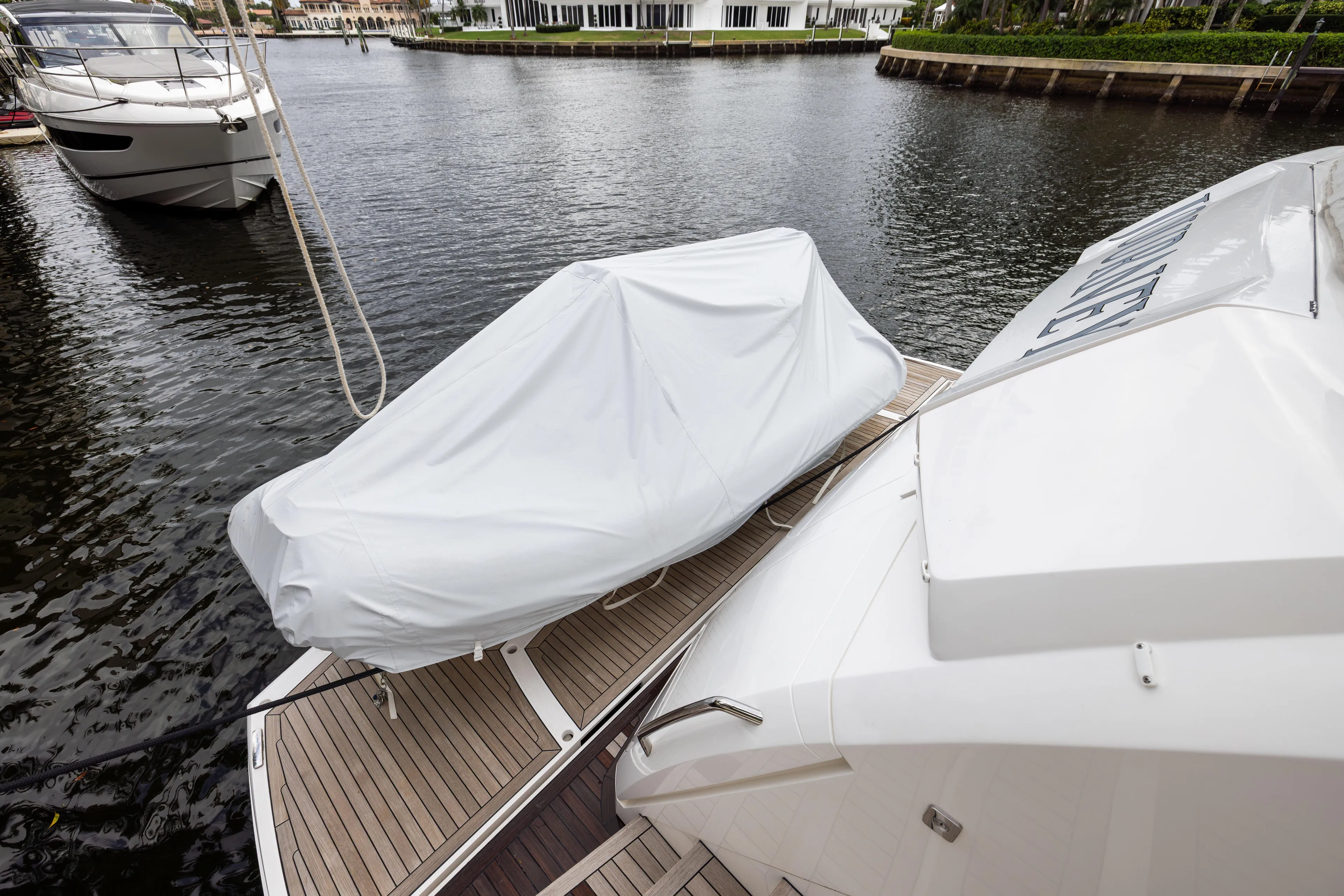 Journey Yacht Photos Pics 2019 Sunseeker 76 yacht with covered equipment on deck, docked by waterfront homes.