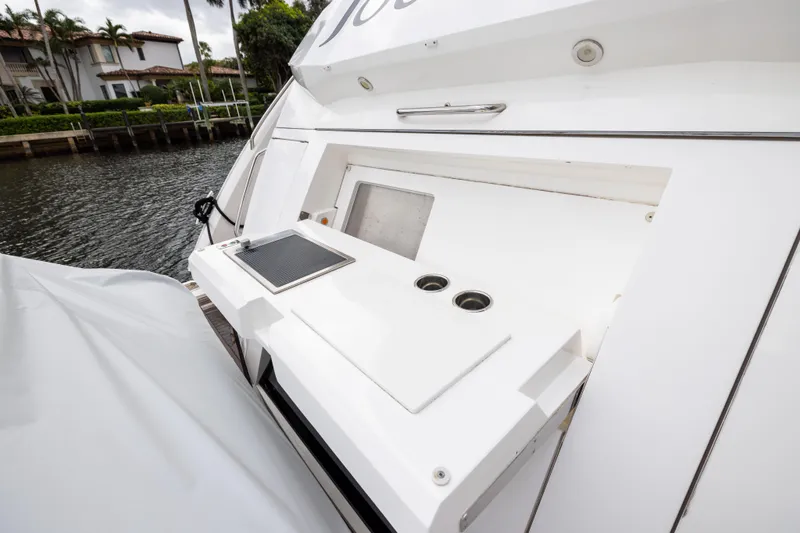 Journey Yacht Photos Pics 2019 Sunseeker 76 yacht deck with built-in sink and storage, docked by waterfront homes.
