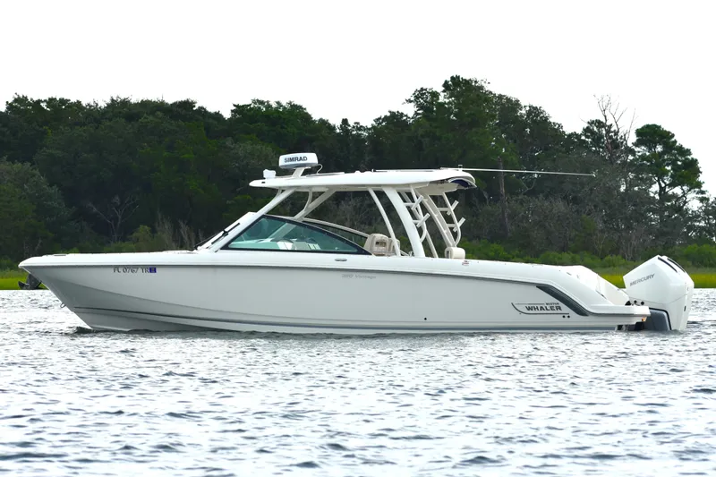  Yacht Photos Pics 2023 Boston Whaler 320 Vantage boat on water, side view with lush greenery background.