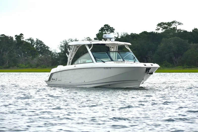  Yacht Photos Pics 2023 Boston Whaler 320 Vantage boat on calm water with lush green background.