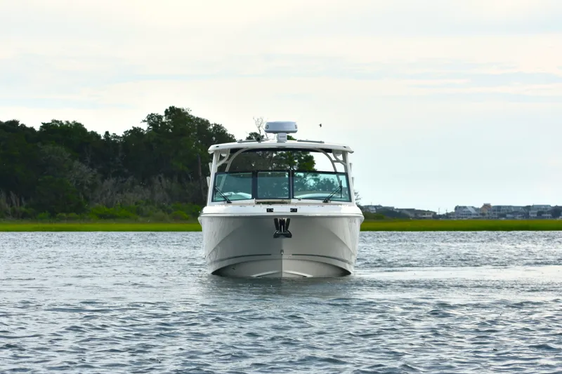  Yacht Photos Pics 2023 Boston Whaler 320 Vantage boat on calm water with scenic background.