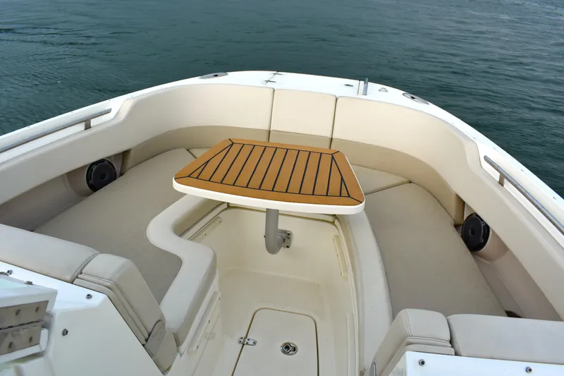  Yacht Photos Pics 2023 Boston Whaler 320 Vantage boat interior with cushioned seating and wooden table.