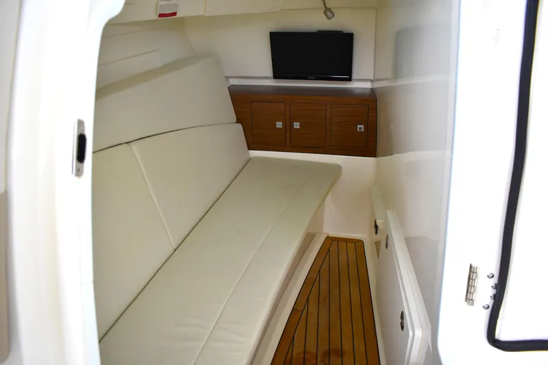  Yacht Photos Pics 2023 Boston Whaler 320 Vantage cabin interior with sofa, TV, and wooden cabinets.