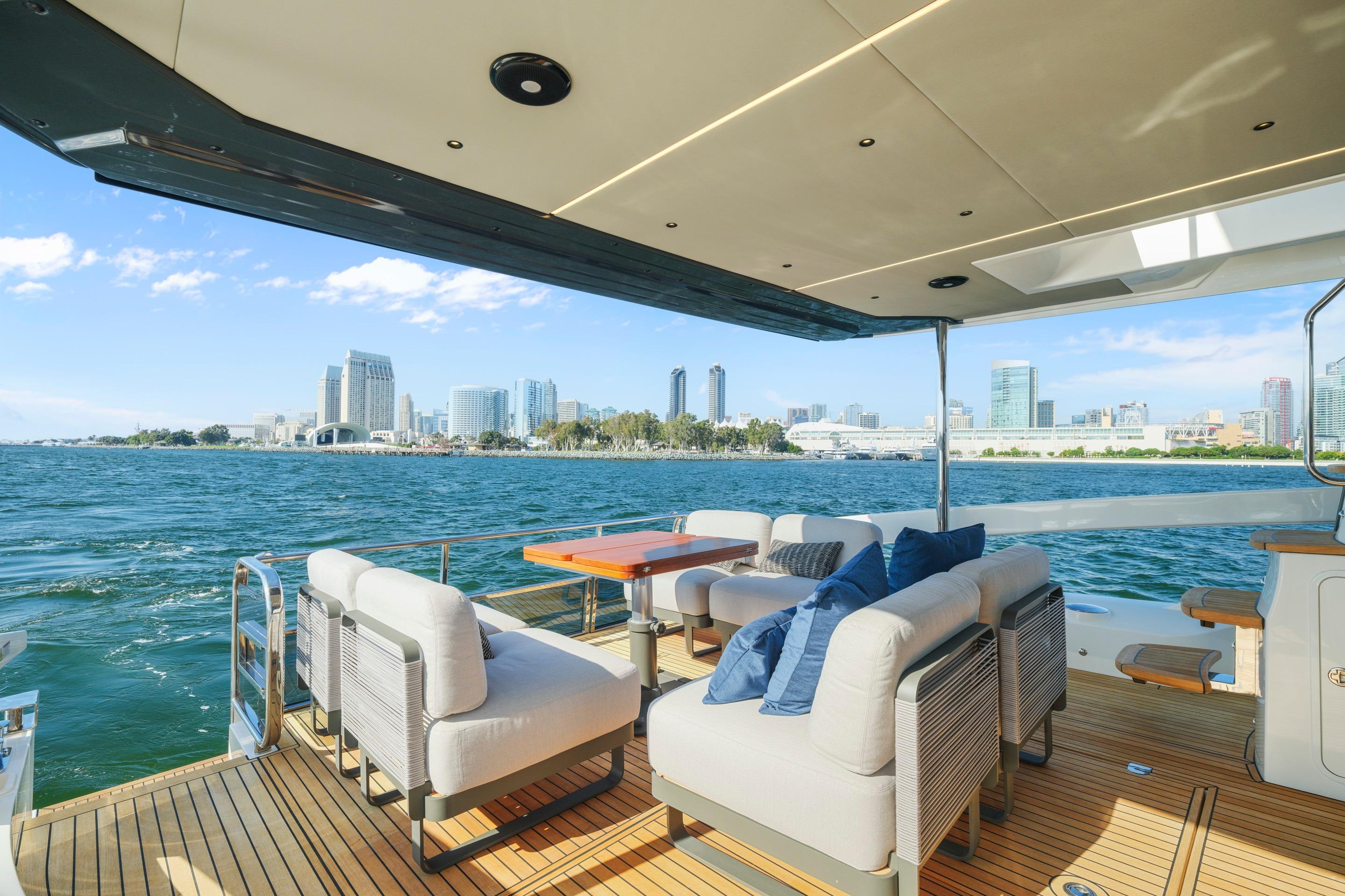Luxurious 2025 Absolute 56 FLY yacht with city skyline view and elegant deck seating.