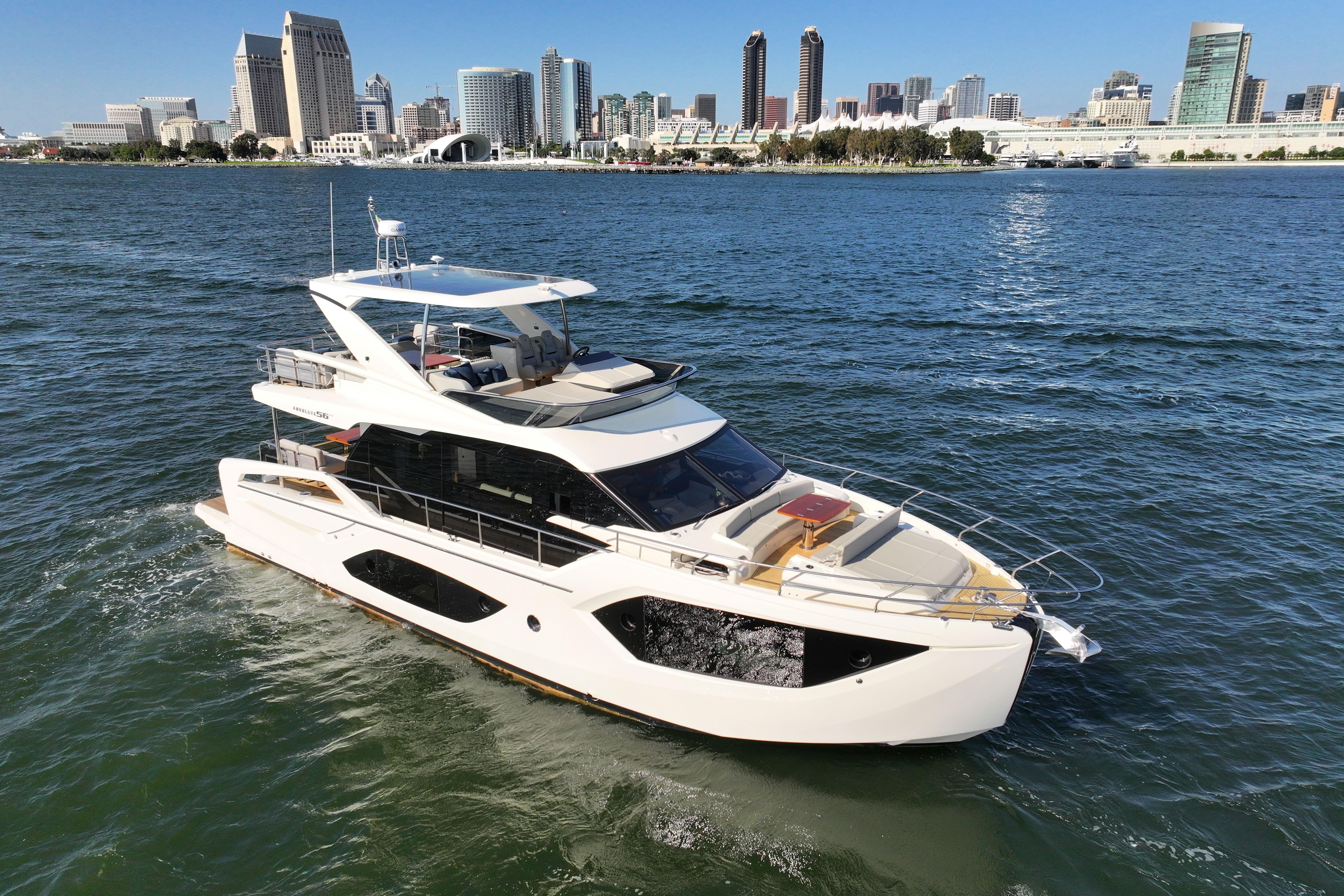 2025 Absolute 56 FLY yacht cruising near city skyline on a sunny day.