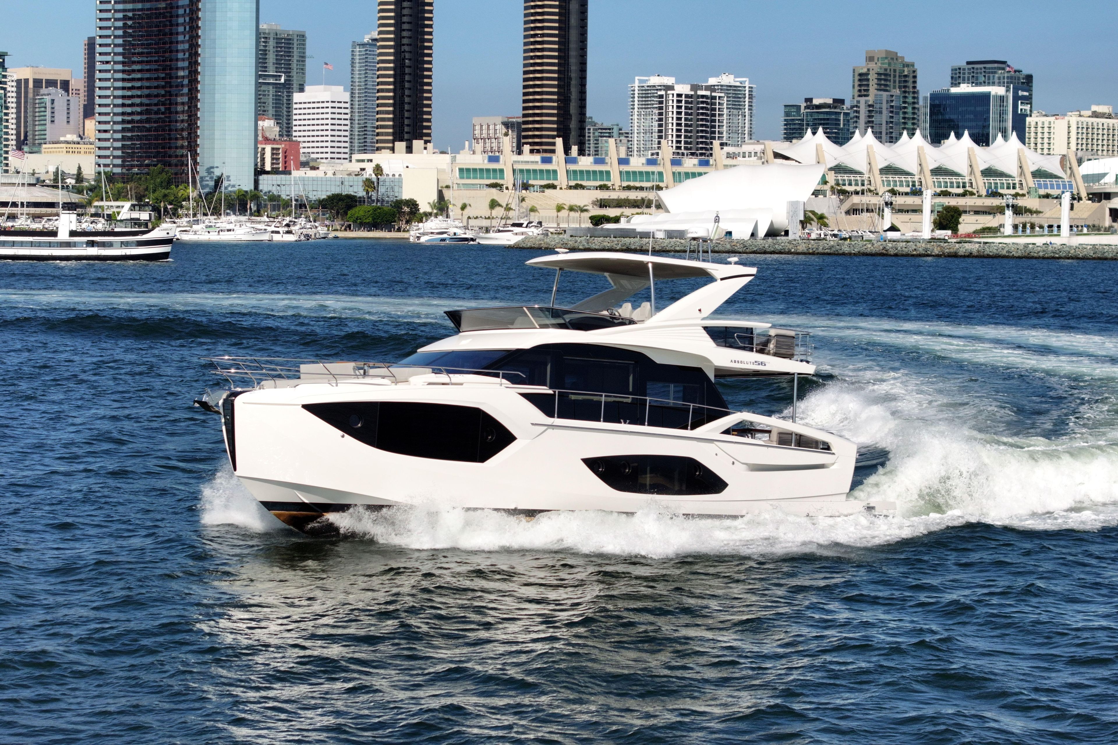 2025 Absolute 56 FLY yacht cruising near city skyline.