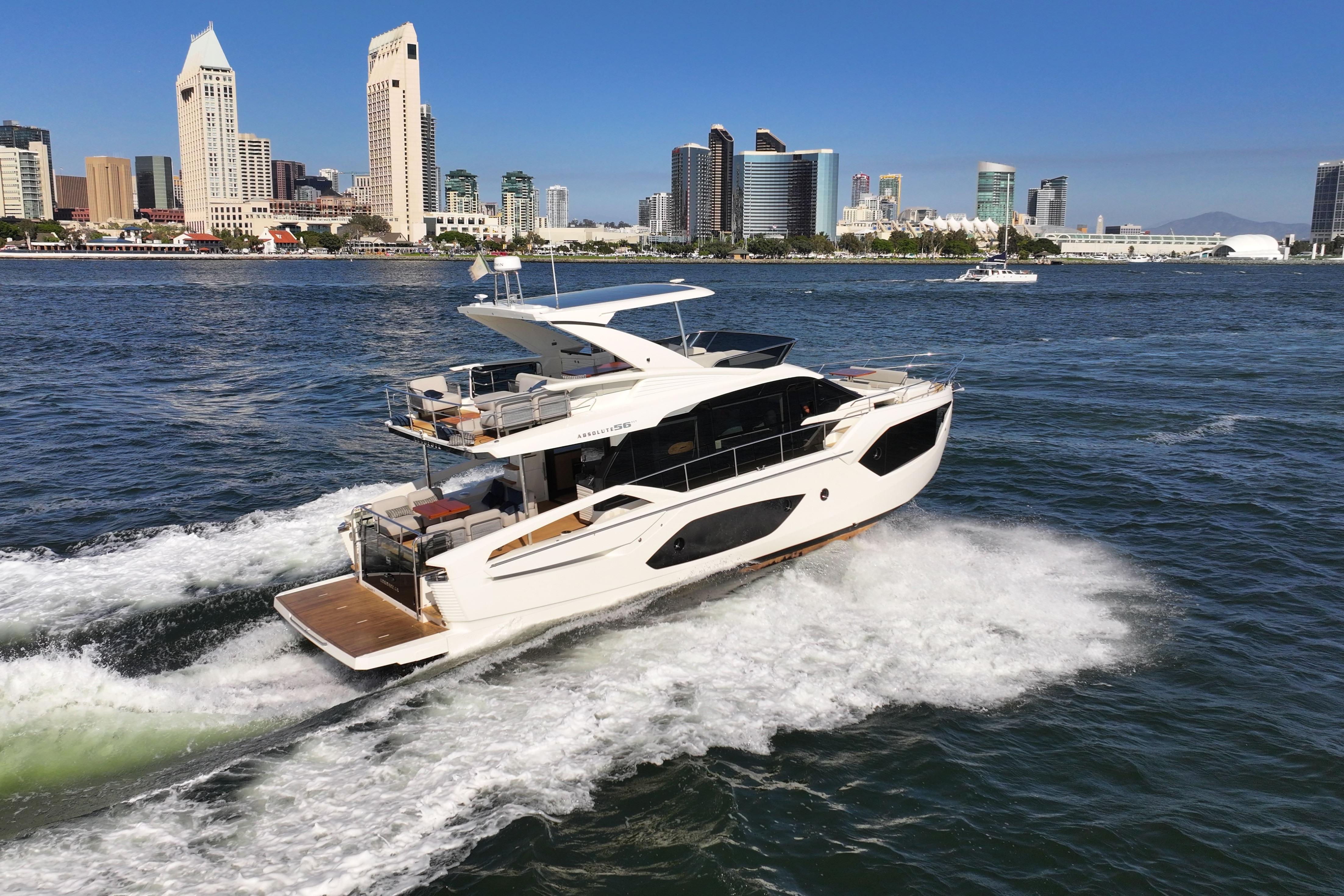 2025 Absolute 56 FLY yacht cruising near city skyline on a sunny day.