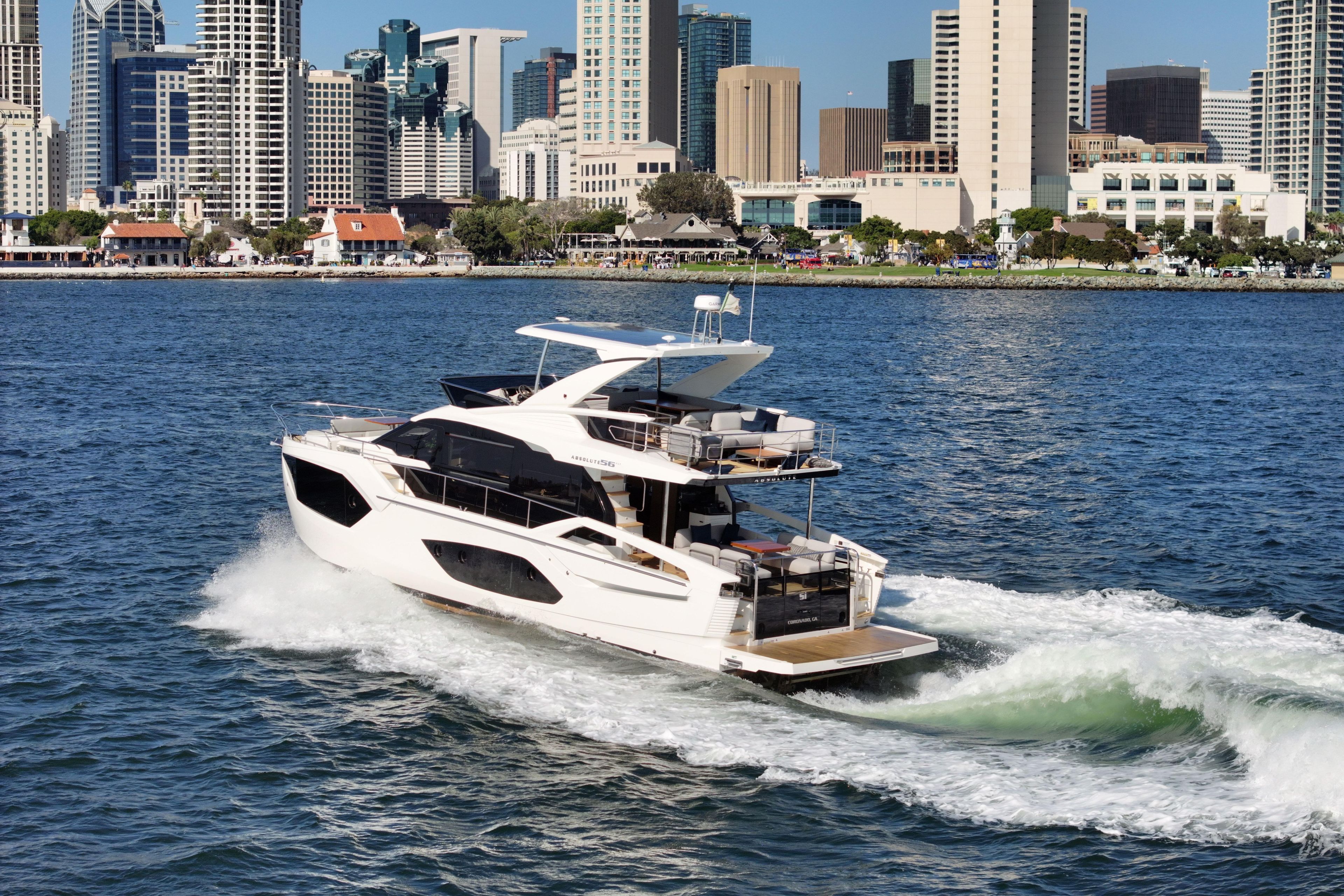 Luxury yacht Absolute 56 FLY 2025 cruising near city skyline.