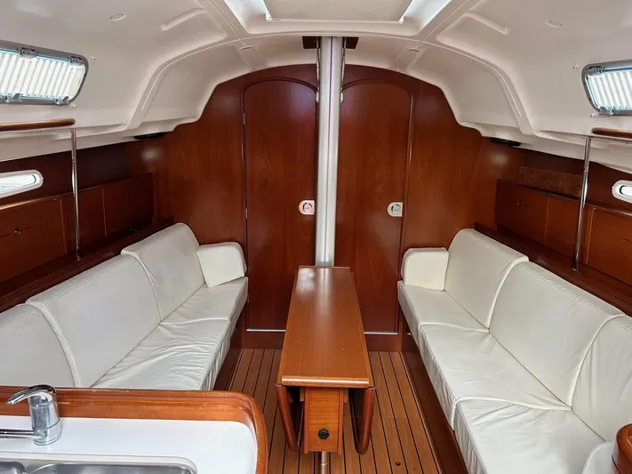 Flaneuse Yacht Photos Pics Interior of 2003 Beneteau 36.7 sailboat with white seating and wooden finishes.