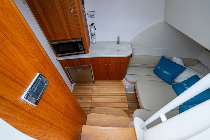 Mrs Diagnosis Yacht Photos Pics 2020 Intrepid 407 Panacea cabin interior with kitchenette, seating, and wooden flooring.