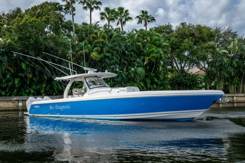 Mrs Diagnosis Yacht Photos Pics 2020 Intrepid 407 Panacea boat in water, surrounded by lush greenery.