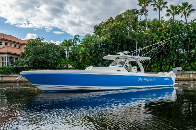 Mrs Diagnosis Yacht Photos Pics 2020 Intrepid 407 Panacea boat on calm water, surrounded by lush greenery.