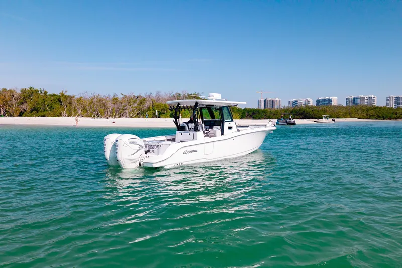  Yacht Photos Pics 2022 Crevalle 33 CSF boat on turquoise water near sandy beach and buildings.