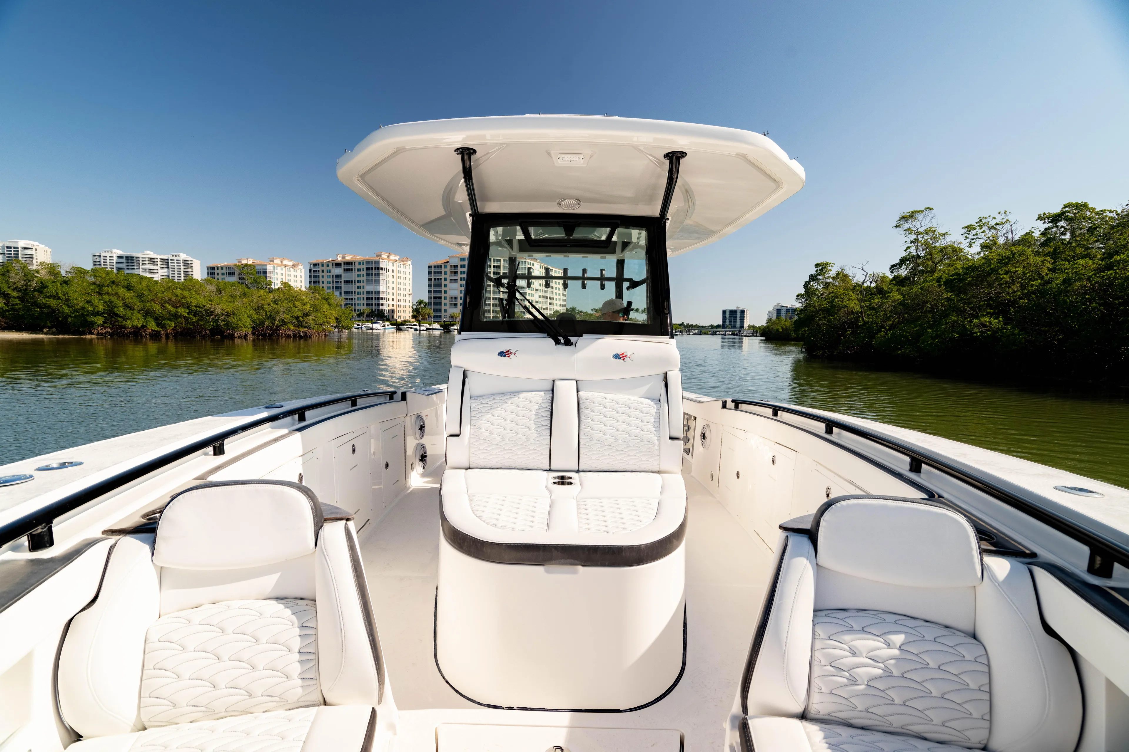  Yacht Photos Pics 2022 Crevalle 33 CSF boat on calm water, surrounded by greenery and buildings.
