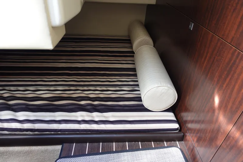  Yacht Photos Pics 2018 Monterey 295 Sport Yacht interior with striped bedding and wooden paneling.