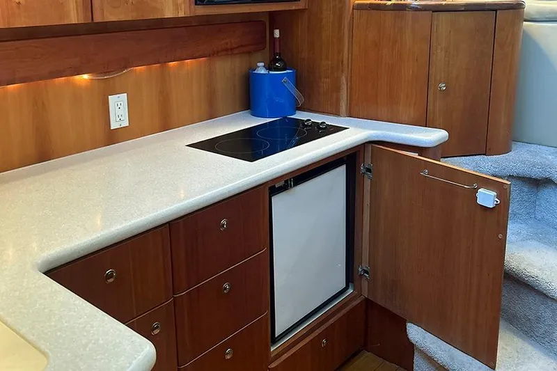  Yacht Photos Pics 2002 Silverton 42 Convertible yacht kitchen with stove, fridge, and wooden cabinetry.