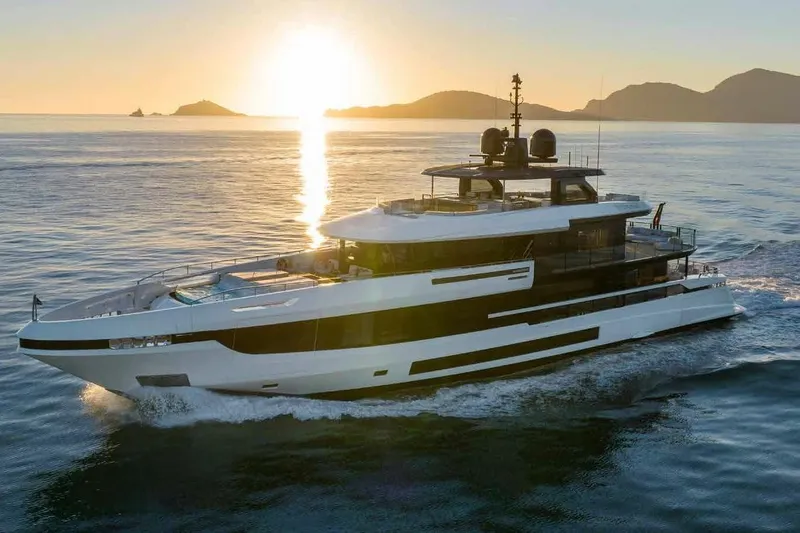 Oceano 44 Yacht Photos Pics 2027 Mangusta Oceano 44 yacht cruising at sunset, with scenic ocean and island backdrop.