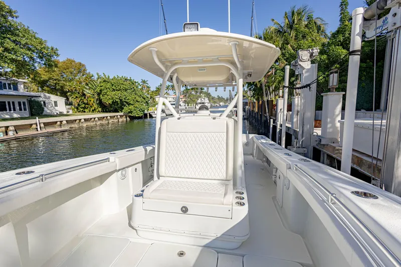 Done Deal Yacht Photos Pics 2015 Yellowfin 32 Offshore boat interior with seating, docked by a scenic waterfront.
