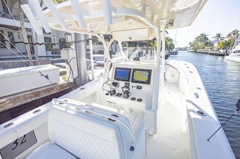 Done Deal Yacht Photos Pics 2015 Yellowfin 32 Offshore boat with modern navigation system, docked in a sunny canal.