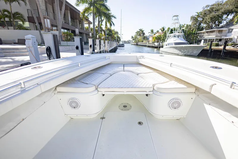 Done Deal Yacht Photos Pics 2015 Yellowfin 32 Offshore boat interior with cushioned seating, docked in a scenic canal.