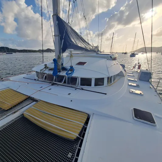  Yacht Photos Pics 2004 Lagoon 570 catamaran on calm waters at sunset, featuring spacious deck and sails.