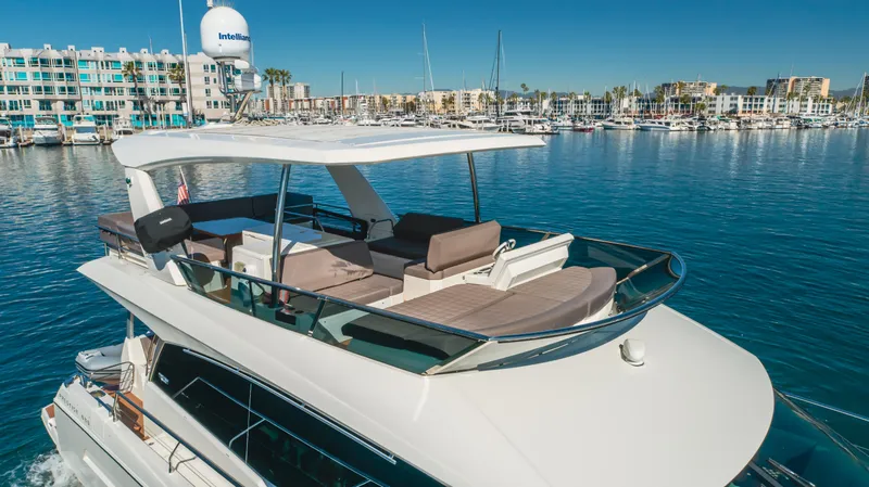 Seaduction Yacht Photos Pics Luxury 2018 Prestige 630 yacht cruising in a marina with modern buildings in the background.