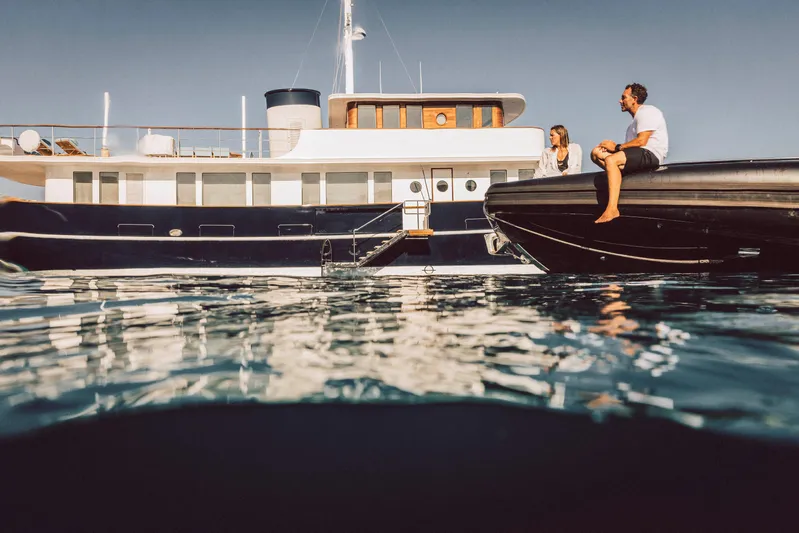 Far Niente Yacht Photos Pics 2024 Hoek Design Motor Yacht with people relaxing on a tender in calm waters.