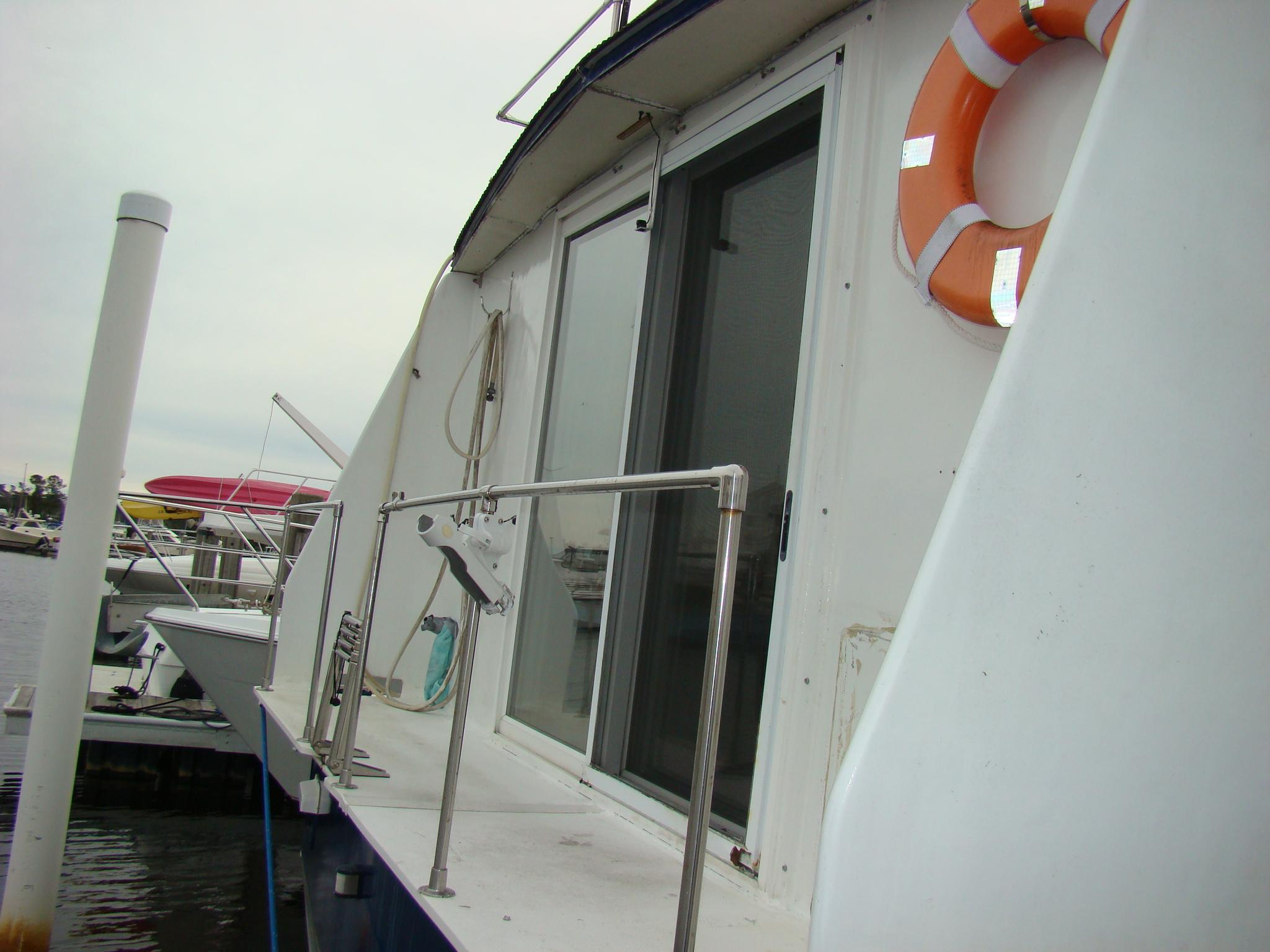 1991 Custom Trawler boat with life ring and sliding door at dock.
