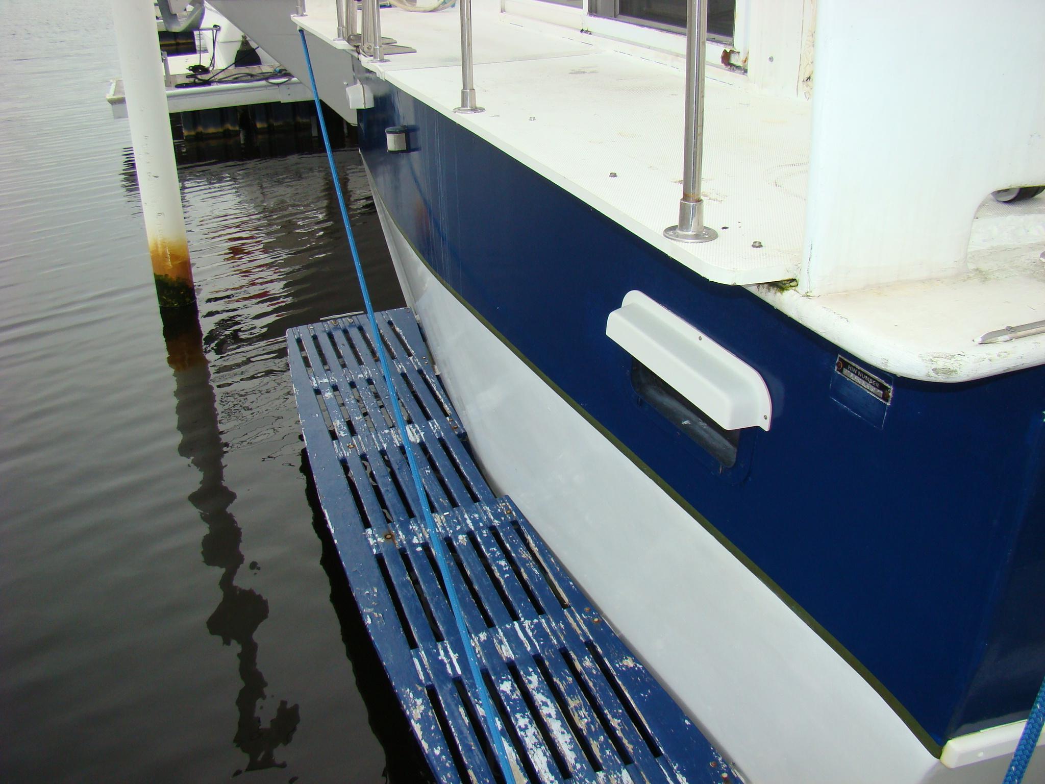 1991 Custom Trawler docked, showing blue and white hull and deck railing.