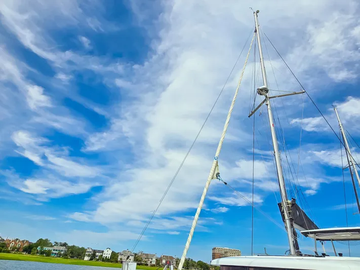 Le Tigre Yacht Photos Pics Sailboat mast of 2019 Lagoon 42 against a vibrant blue sky with clouds.