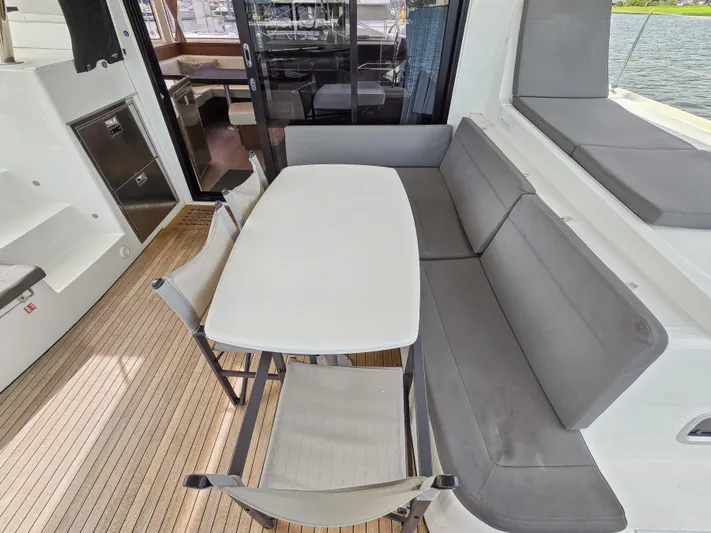Le Tigre Yacht Photos Pics Outdoor seating area on 2019 Lagoon 42 catamaran with table and cushioned benches.