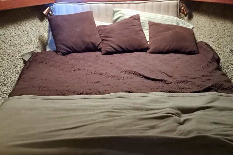 Jen & Tonic Yacht Photos Pics Bed in the cabin of a 1986 Post Sportfisher boat with brown pillows and blankets.