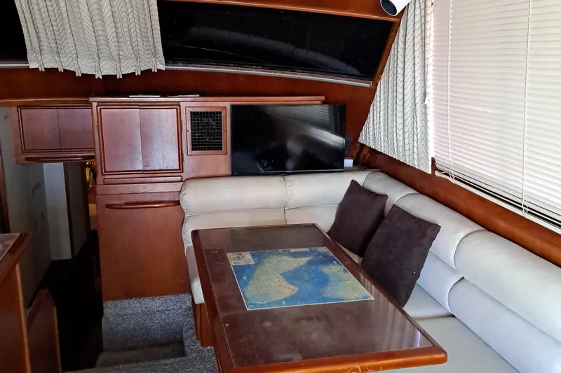 Jen & Tonic Yacht Photos Pics 1986 Post Sportfisher boat interior with dining area, map table, and beige seating.