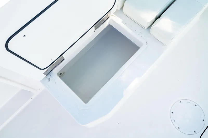  Yacht Photos Pics 2022 Edgewater 262 CX boat storage compartment, open and empty, with white seating nearby.
