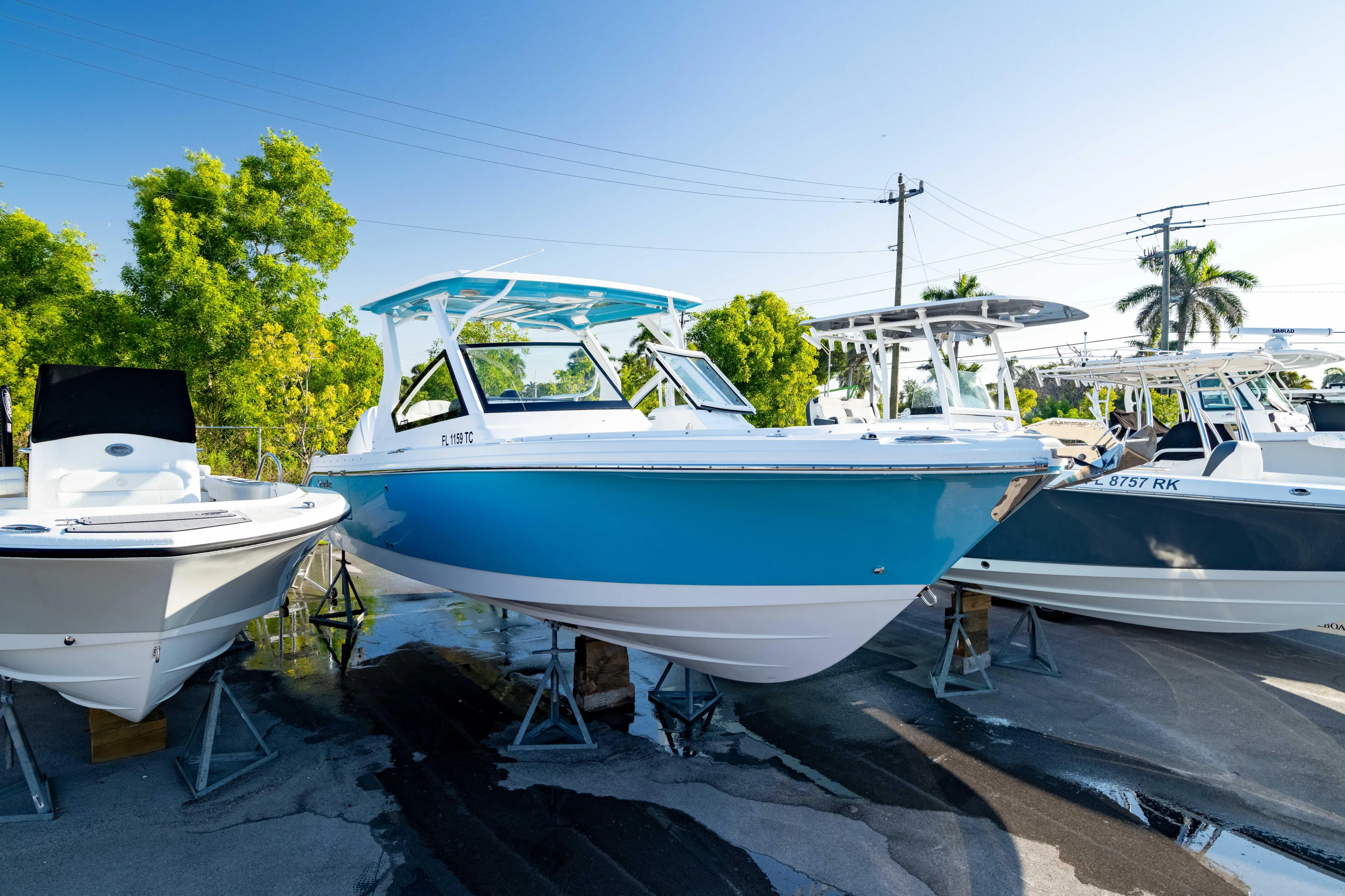  Yacht Photos Pics 2022 Edgewater 262 CX boat displayed outdoors on stands, surrounded by trees and other boats.
