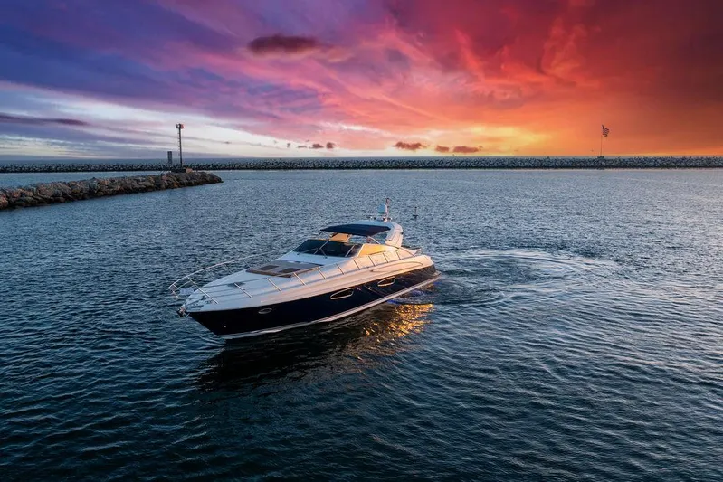 Rhapsody Yacht Photos Pics Riva 59 Mercurius yacht cruising at sunset, 2004 model, vibrant sky in background.