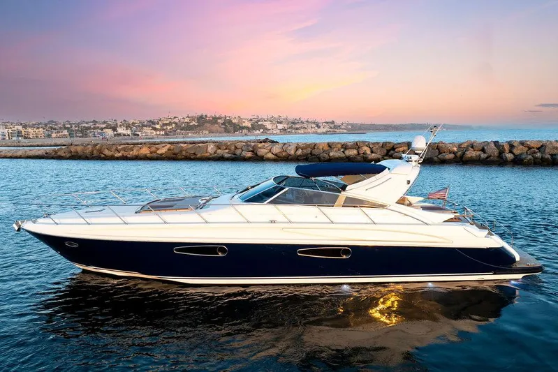 Rhapsody Yacht Photos Pics 2004 Riva 59 Mercurius yacht cruising at sunset near rocky shoreline.