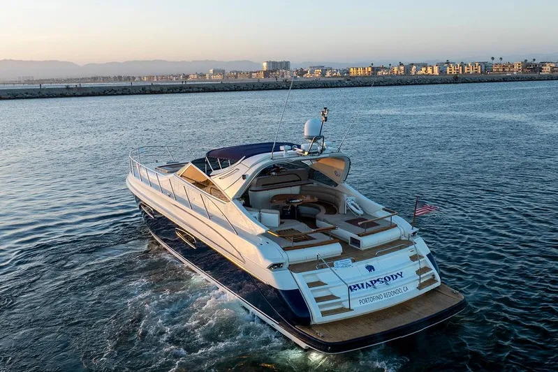 Rhapsody Yacht Photos Pics Luxurious 2004 Riva 59 Mercurius yacht cruising on serene waters at sunset.