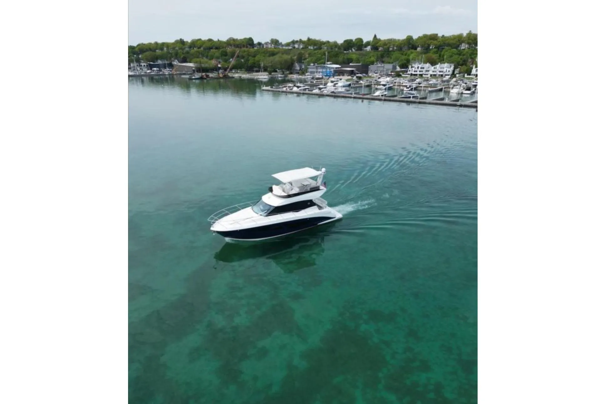 2023 Regal 42 Fly yacht cruising in clear waters near a marina.