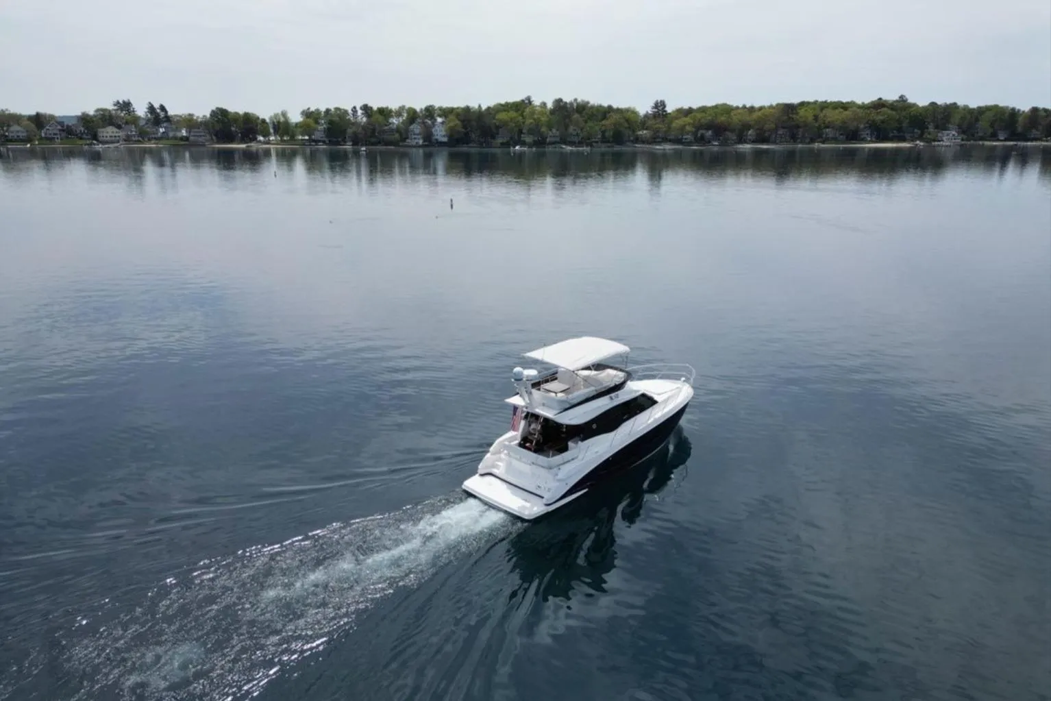 2023 Regal 42 Fly yacht cruising on a calm lake with scenic shoreline.