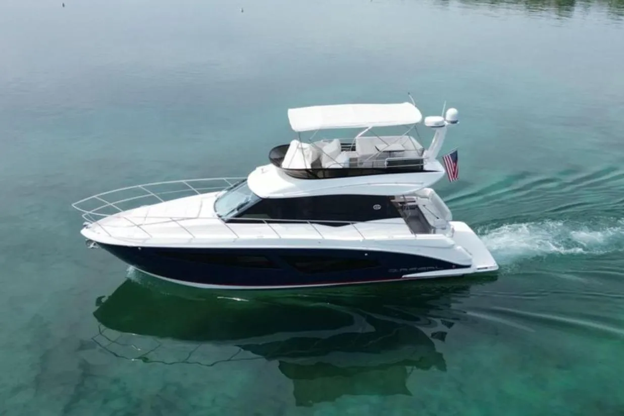 2023 Regal 42 Fly yacht cruising on a serene lake with lush shoreline.