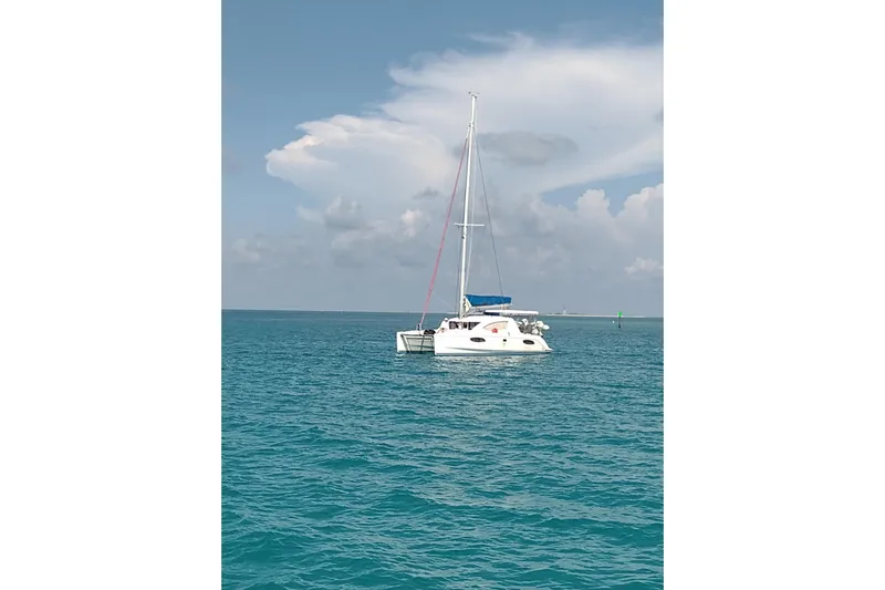 Lovely Cruise Yacht Photos Pics Sailing catamaran Leopard 38, 2011 model, on calm turquoise waters under a cloudy sky.