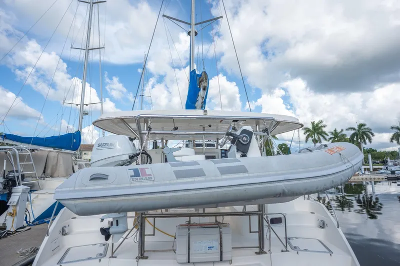 Lovely Cruise Yacht Photos Pics 2011 Leopard 38 catamaran with dinghy, docked under a cloudy sky, palm trees in background.