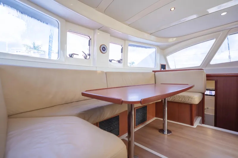 Lovely Cruise Yacht Photos Pics Interior of 2011 Leopard 38 catamaran with beige seating and wooden table.