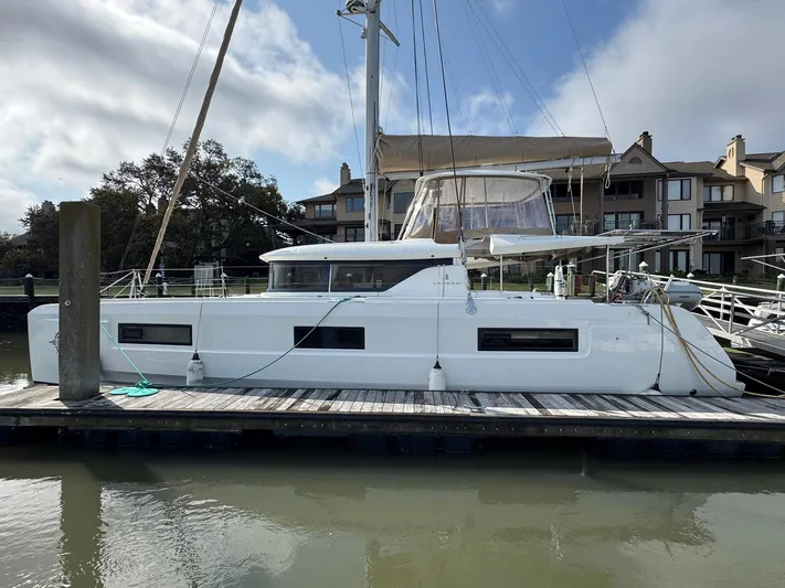 Eden Yacht Photos Pics 2022 Lagoon 46 catamaran docked at a marina, with residential buildings in the background.