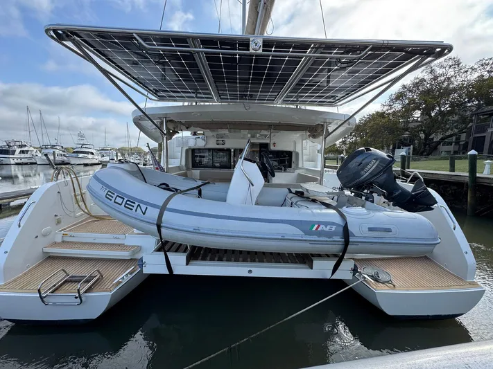 Eden Yacht Photos Pics 2022 Lagoon 46 catamaran with dinghy, docked at marina, featuring solar panels.