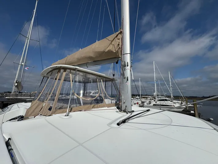 Eden Yacht Photos Pics 2022 Lagoon 46 catamaran docked, featuring beige sail cover and clear canopy under a blue sky.