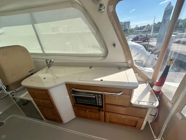 Reveille Yacht Photos Pics 2013 Back Cove 34 yacht interior with kitchenette, featuring sink, stove, and wooden cabinetry.