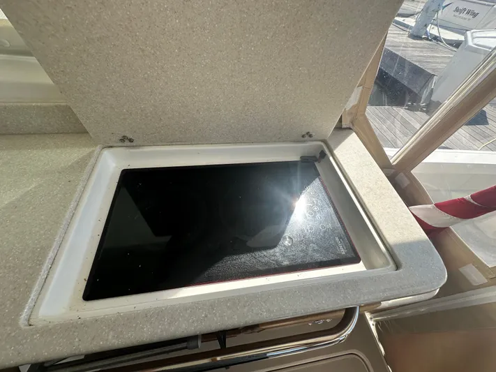 Reveille Yacht Photos Pics 2013 Back Cove 34 yacht interior with open stove cover, sunlight reflecting on surface.